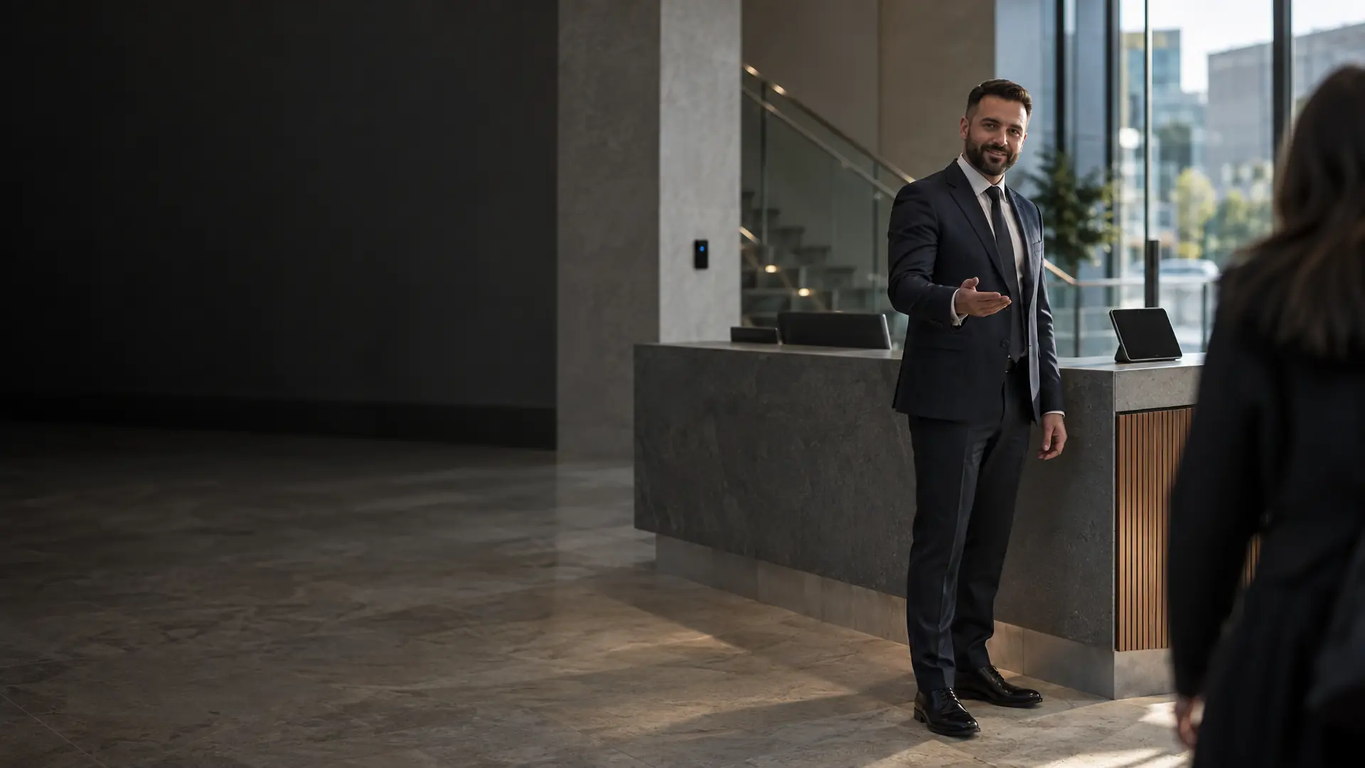 Front of house security officer greeting a visitor at an office reception desk